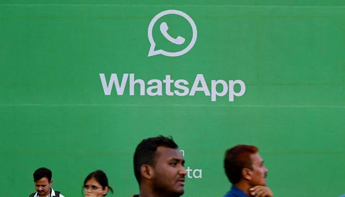 Tourists walk past a display of messaging app WhatsApp in Mumbai on August 25, 2023. — AFP