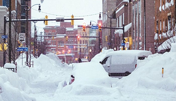 Vehicles are seen trapped under heavy snow in the streets of downtown Buffalo. — AFP/File