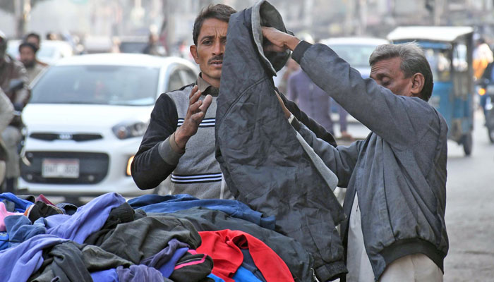 A man is seen buying jackets from a street vendor to counter the cold weather in Karachi on January 8, 2024. — Online