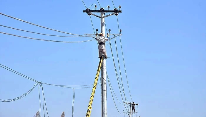 Workers seen on an electric pole in Islamabad on October 26, 2023. — APP