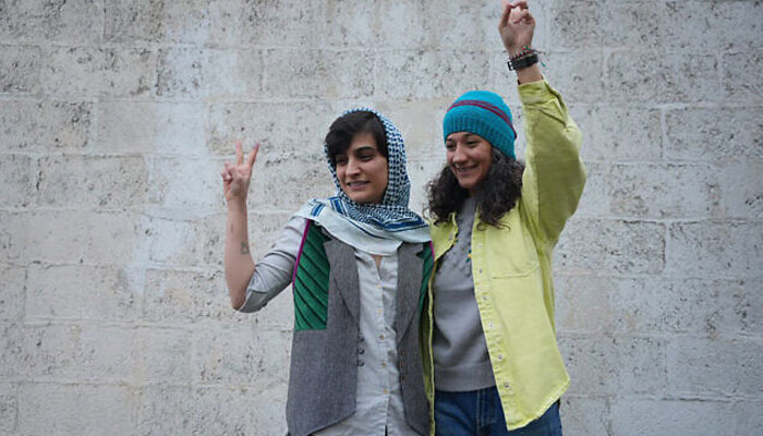 This picture taken and released by the Sharq News Online on January 14, 2024, shows Iranian journalists Niloufar Hamedi (R) and Elaheh Mohammadi (L) flashing the sign of victory after they were released from Evin prison on bail in Tehran. —AFP