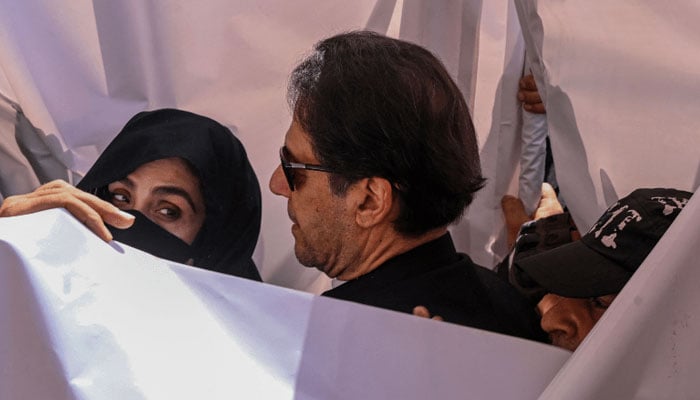 Former prime minister Imran Khan with his wife Bushra Bibi arrive to appear at a high court in Lahore on May 15, 2023. — AFP