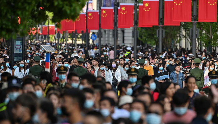 People walk along a pedestrian street during a Labor Day holiday in Shanghai on May 1. — AFP/File