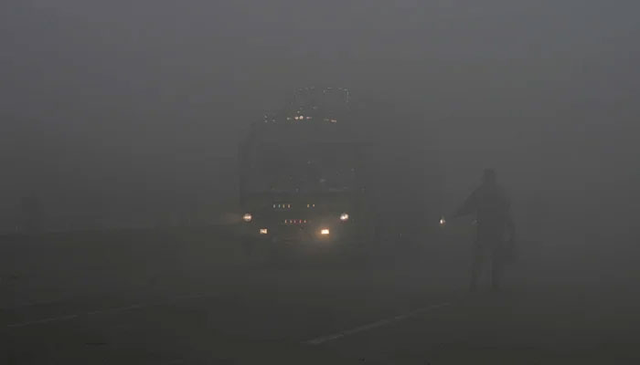 Commuters make their way along a street amid heavy smog in Lahore on December 14, 2023. — AFP