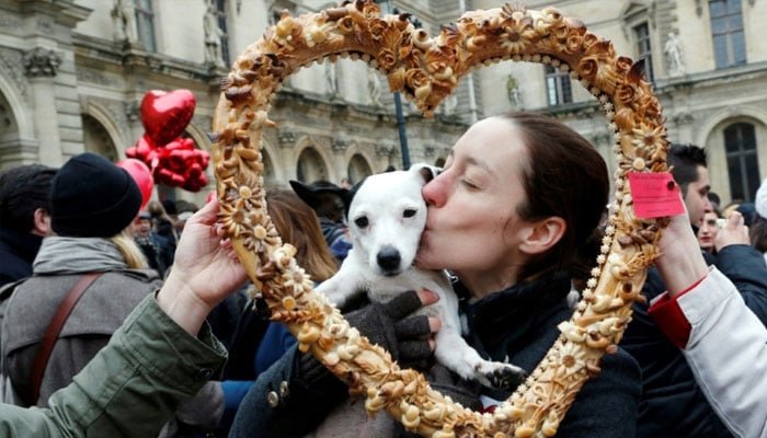 True love: a woman and her Valentines Day date pose behind a heart-shaped pastry during a February 14 Paris flash mob. —AFP/file