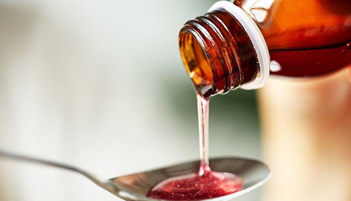 A syrup being poured into a spoon. — Robitussin