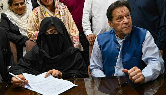 Imran Khan (R), along with his wife Bushra Bibi (L), looks on as she signs surety bonds for bail in various cases, at a registrar office in the Lahore High Court on July 17, 2023. — AFP