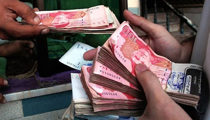 A person can be seen holding notes of Pakistani currency Notes in the hands. —AFP/File