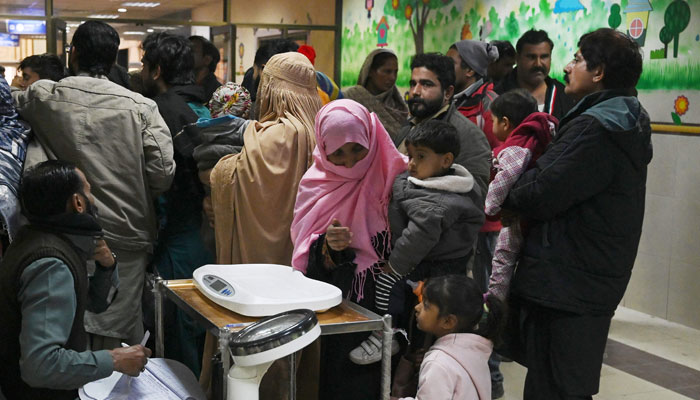 Parents wait with their child suffering from pneumonia, at the Childrens Hospital in Lahore on January 31, 2024. — AFP