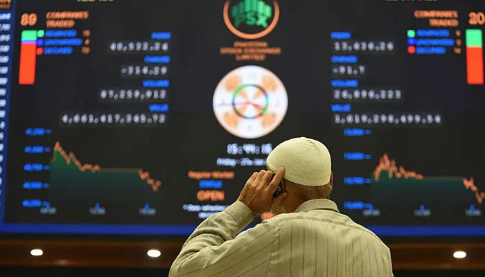 A broker talks on a phone as he watches latest share prices at the Pakistan Stock Exchange in Karachi on January 27, 2023. — AFP