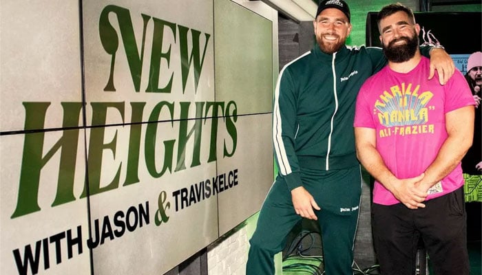 Travis Kelce (left) with brother Jason Kelce standing next to their podcast show poster, New Heights. — Forbes/File