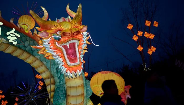 People stand next to a dragon figure at a new years fair in Beijing on February 4, 2024. — AFP