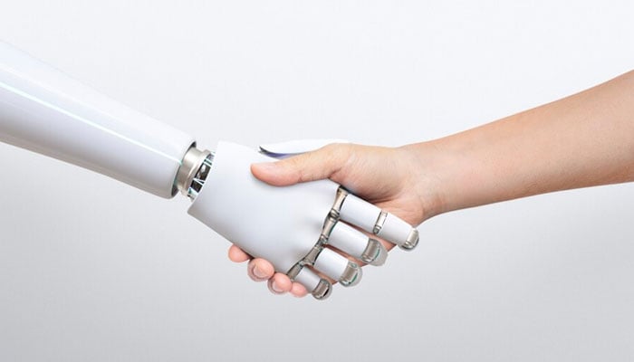 The image shows a robot hand shaking hands with a human. — Freepik