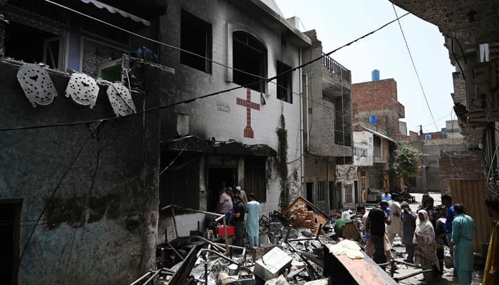 Police officials and residents stand amid debris outside the torched Saint John Church in Jaranwala on the outskirts of Faisalabad on August 17, 2023. — AFP