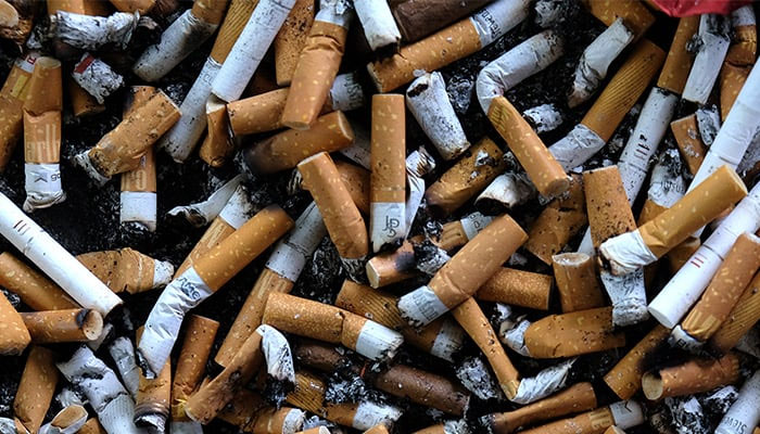 An ashtray filled with cigarette butts is seen on an outdoor smoking stand at a bus stop. — AFP/File
