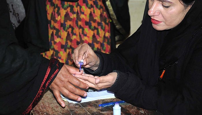 Polling officer marks the thumb of a woman voter before issuing ballot paper at a polling station in Multan during general elections on February 8, 2024. — APP