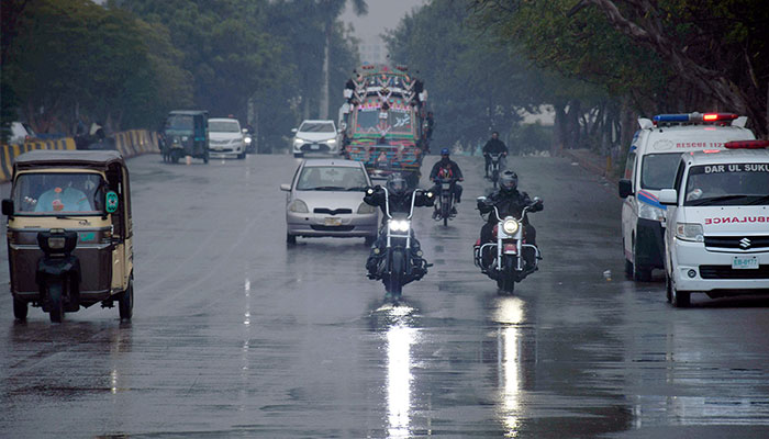 Commuters make their way at a road amid rain showers in the Provincial Capital