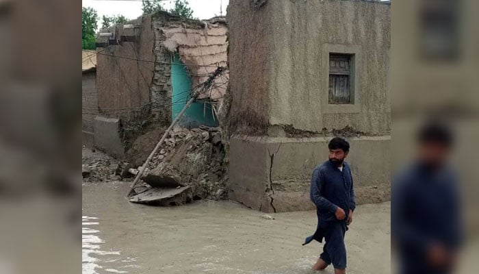 A man is wading through rainwater in Gwadar. —X/@MahrangBaloch_