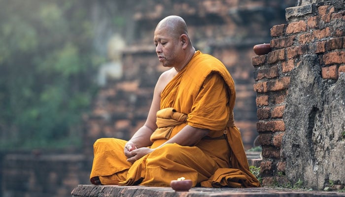 The image shows a Buddhist monk sitting. — Pixabay