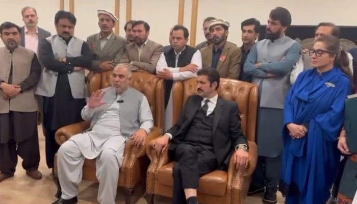 PTI leaders Sher Afzal Marwat (R) and Asad Qaiser (L) sitting on sofa chairs at an undisclosed location are recording a video statement against two YouTubers on March 4, 2024. —@sherafzalmarwat/X