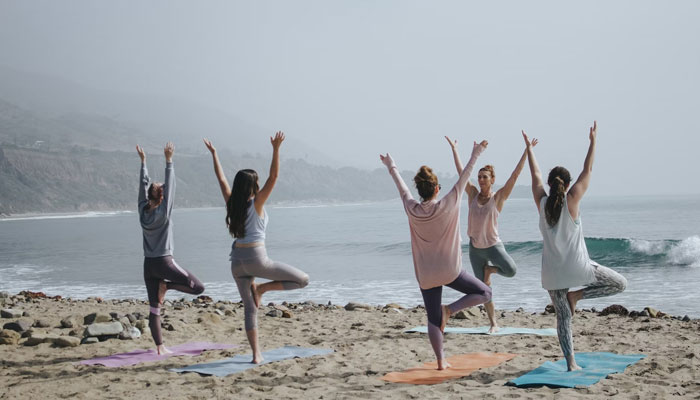 A representational image of a group doing yoga by the sea. — Unsplash