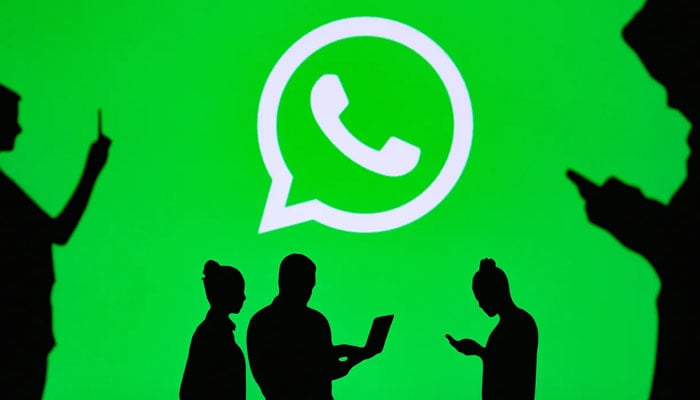 An illustration depicting people using electronic gadgets with the WhatsApp logo as the background. — WhatsApp/File
