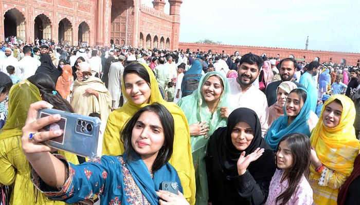 A girl is taking a selfie with her family after offering Eid-ul-Fitr prayer at Badshahi Masjid on April 22, 2023. —APP