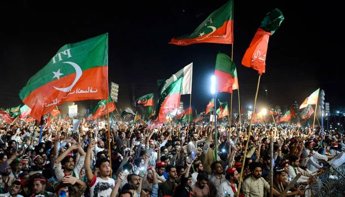 Members of the PTI hoist their party flags at a public gathering in this undated picture. — AFP/File