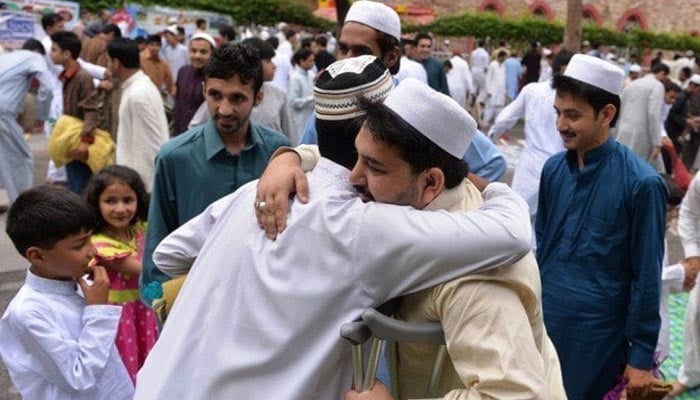 People exchange Eid greetings after offering Eid ul Fitr prayers in Islamabad on July 29, 2014. — AFP
