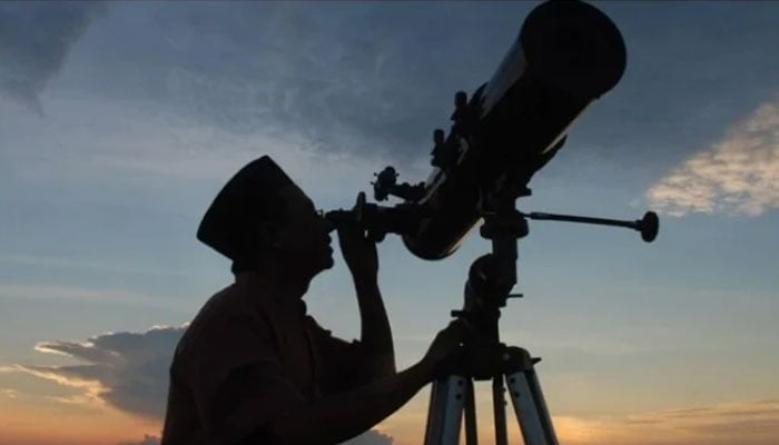 A man observes the moon through a telescope. --AFP/File