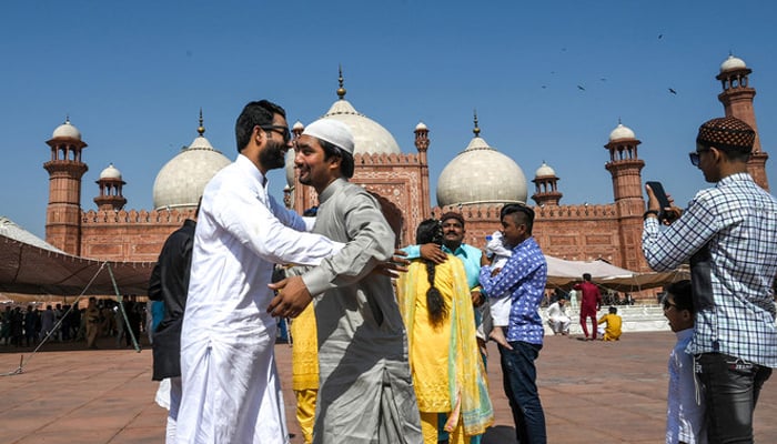 Muslims hug eachother after offering Eid ul Fitr prayers at the Badshahi Mosque in Lahore on May 24, 2020. — AFP