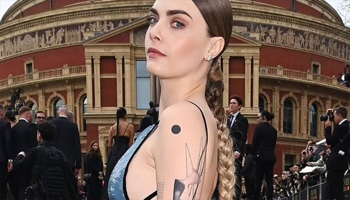 Cara Delevingnes topless tattoo display sparks typo concerns among fans.