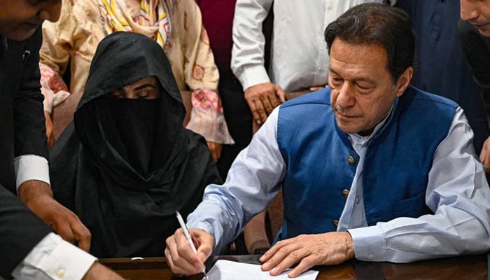 Pakistans former prime minister, Imran Khan (right) pictured alongside his wife Bushra Bibi as he signs surety bonds for bail in various cases, at a registrars office in the Lahore High Court, in Lahore on July 17, 2023. — AFP