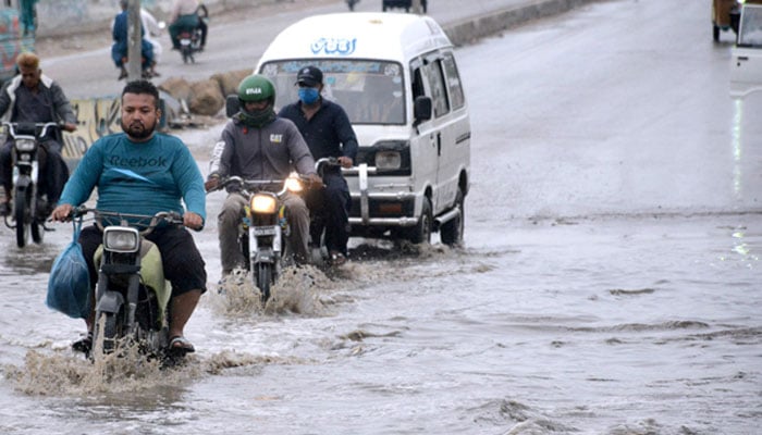 Commuters pass through stagnant rain water at Karachis Korangi Road on April 14, 2024. — APP