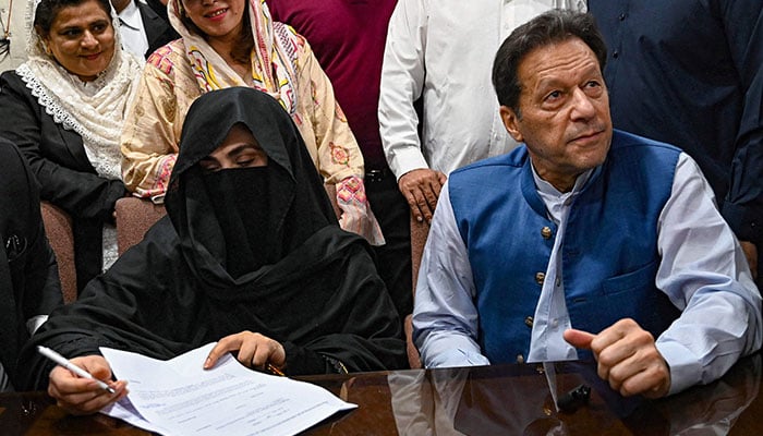 Pakistan´s former Prime Minister, Imran Khan (R) along with his wife Bushra Bibi (L) looks on as he signs surety bonds for bail in various cases, at a registrar office in the High court, in Lahore on July 17, 2023. — AFP
