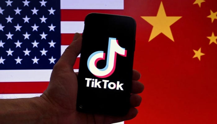 A representational image of a person holding a smartphone with TikTok logo on its phone screen. — AFP/File