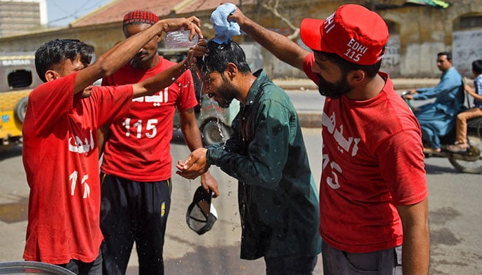 Volunteers of Edhi Foundation cool down a man with water during a hot day in Karachi on April 11, 2021. — AFP