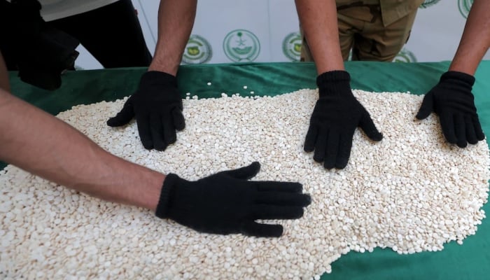 Officers of the General Directorate of Narcotics Control of Saudi Arabias Interior Ministry sort through tablets of Captagon, an amphetamine seized in Jeddah this spring. —AFP
