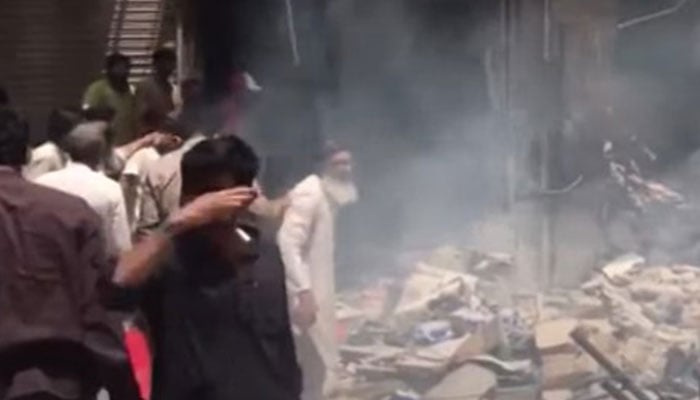 People gather around the shop which was subjected to a cylinder explosion in Karachis New Challi area on April 30, 2024. — Screengrab/YouTube/Geo News Live