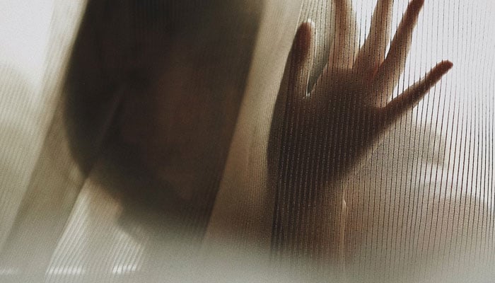 Representational image of a woman behind a curtain. — Unsplash.