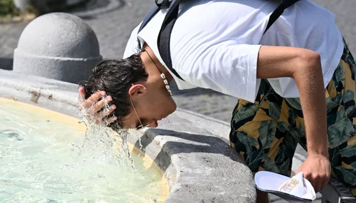 A boy pours water over his head to cool off at the fountain in Piazza del Popolo in Rome, Italy. — AFP File