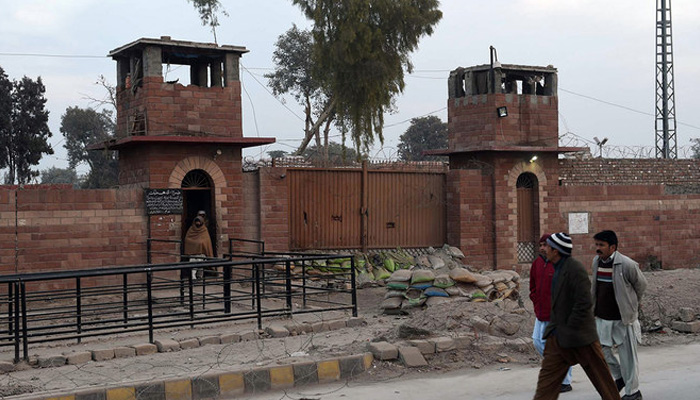Pedestrians walk past the central jail in Peshawar on December 31, 2014. — AFP