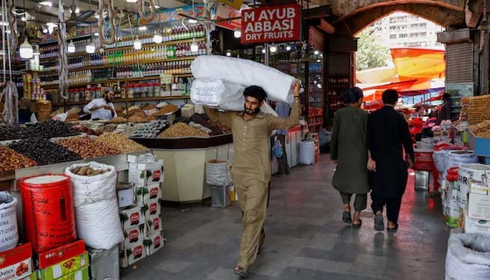 A man walks with sacks of supplies on his shoulder to deliver to a nearby shop at a market in Karachi, Pakistan June 11, 2024.— Reuters