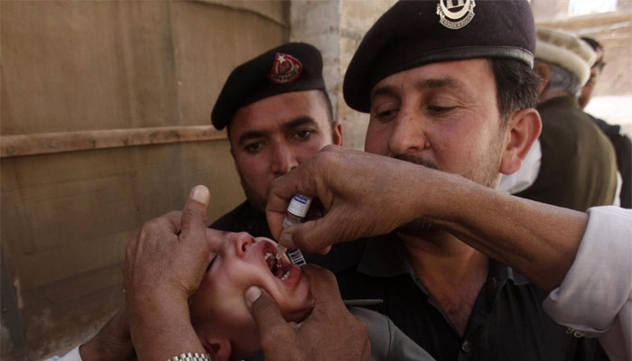 Polio workers give polio vaccine drops to a child as police stand guard during a vaccination campaign in Peshawar, the capital of Khyber-Pakhtunkhwa province.— Reuters/File
