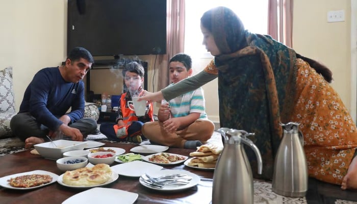 Daughter of Afghan refugee Wazir Khan Zadran serves her father a hot tea as they have breakfast, in Bowling Green, Kentucky, US, April 29, 2025. — Reuters