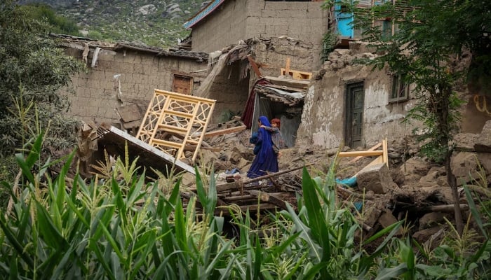 A woman carries a child as she walks past a damaged house following a deadly magnitude-6 earthquake that struck Afghanistan on Sunday, in Mazar Dara, Kunar province, Afghanistan, September 2, 2025. — Reuters