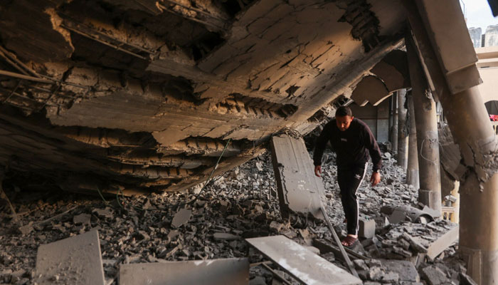 A man walks through the rubble of a destroyed section of a school-turned-camp following an Israeli strike in Gaza City on March 18, 2025. — AFP