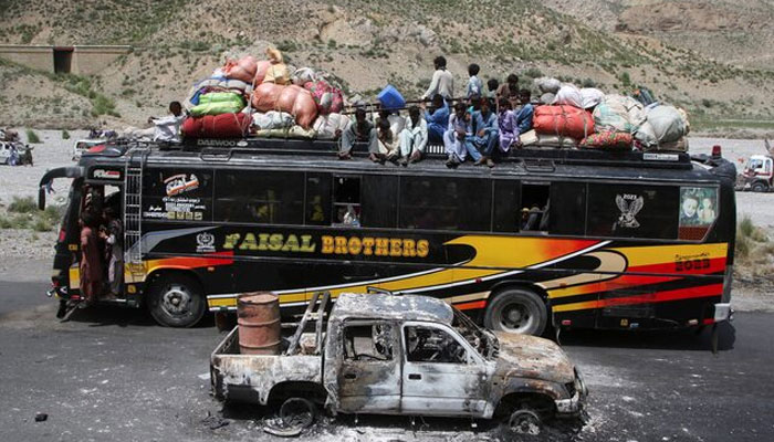 A bus with passengers sitting on the roof with belongings, drives past a damaged vehicle, a day after separatist militants conducted deadly attacks, in Bolan district of Pakistans restive province of Balochistan, Pakistan August 27, 2024. — Reuters