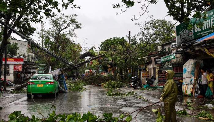 People watch as workers remove fallen trees and electric polls from a road after Typhoon Bualoi makes landfall in Nghe An province, Vietnam, September 29, 2025. — Reuters