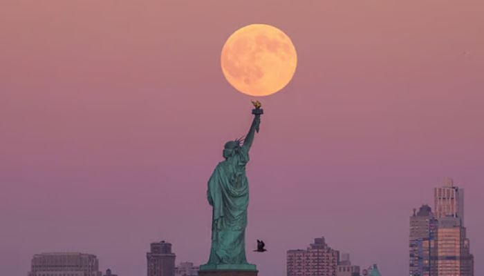 The Harvest Supermoon rises behind the Statue of Liberty and the Brooklyn skyline,New Jersey